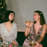 Three Women Laughing Beside Christmas Tree