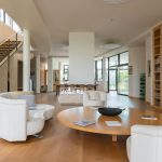 Large apartment with modern interior and soft armchair with white sofa near stairs